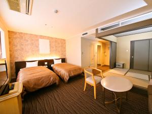 ein Hotelzimmer mit 2 Betten und einem Tisch in der Unterkunft Resort Hotel Tateshina in Chino