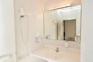 a white bathroom with a sink and a mirror at Stadthotel Engel in Ettlingen