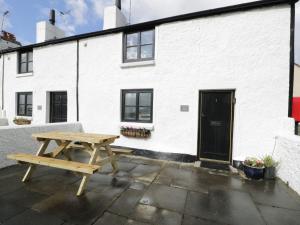 a wooden picnic table in front of a white building at Menai Cottage in Llanfairpwllgwyngyll