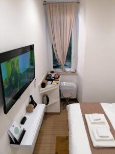 Habitación blanca con cama y TV de pantalla plana. en Abbracci leandra Rooms, en Civitavecchia