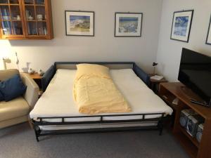 een bed in een kamer met een bank en een tv bij Ferienwohnung-Silvie-8 in Westerland