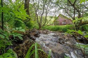 a stream in front of a red house with a river at Inverskilavulin Estate Lodges in Fort William