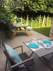 une table avec deux chaises et une table de pique-nique avec des plaques bleues dans l'établissement villa les champs de knokke, à Knokke-Heist