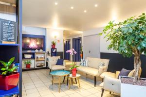 a living room with a couch and chairs and a tv at Aparthotel Adagio Access La Défense - Léonard De Vinci in Courbevoie