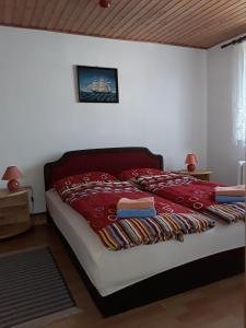 a bedroom with a bed with a red blanket on it at Ferienwohnung-Lalka in Altenkirchen