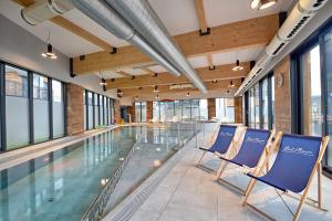 a swimming pool with blue chairs in a building at Apartamenty Bel Mare SeaView by Rent like home in Międzyzdroje