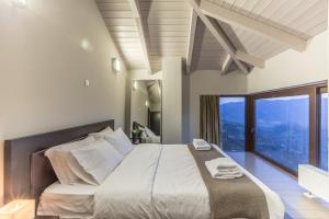 a bedroom with a large bed with a large window at White Hills Villas in Arachova