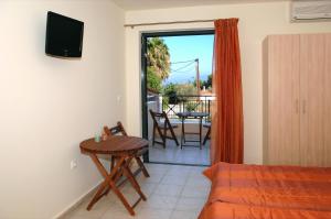a room with a bed and a table and a balcony at Achladi Beach in Achladi