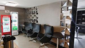 una sala de espera con sillas negras y una máquina de refrescos en Hotel Econotel, en Brasilia