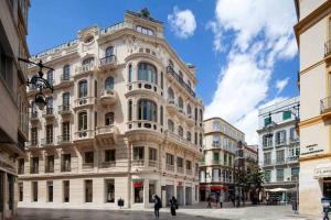 un gran edificio blanco con gente caminando delante de él en Wanderlust Malaga Apartamentos Atico, en Málaga
