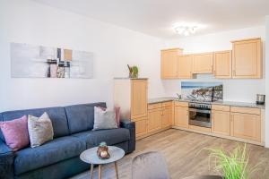 ein Wohnzimmer mit einem blauen Sofa und einer Küche in der Unterkunft Laube35 Central City Apartments in Sterzing