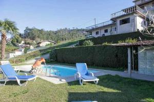 a swimming pool with two chairs and a man in a yard at Casa Rural do Salgueirinho in Santo Tirso