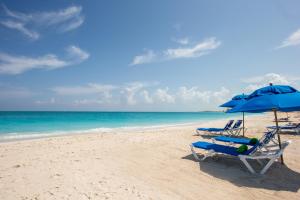 two chairs and an umbrella on a beach at Ports of Call Resort in Grace Bay