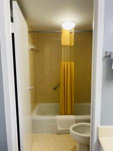 a bathroom with a yellow shower curtain and a toilet at Traveler's Place Inn & Suites in Scottsboro