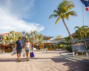 Ein Mann und eine Frau gehen eine Straße mit Palmen entlang in der Unterkunft Ports of Call Resort in Grace Bay