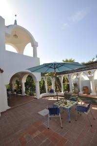 a patio with two chairs and a table with an umbrella at Villa Eva in Anacapri