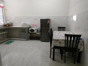 a kitchen with a table with chairs and a refrigerator at Villa Pulai Indah Temerloh in Temerloh