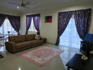 a living room with a brown couch and some windows at Villa Pulai Indah Temerloh in Temerloh
