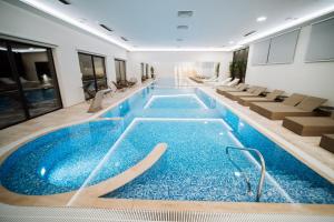 a large swimming pool in a building with chairs at Hotel Barcode Wellness & Spa in Sombor