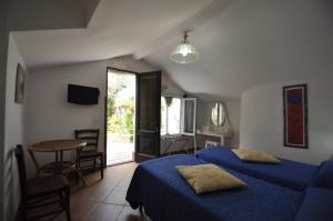a bedroom with a blue bed and a table and a window at Villa Eva in Anacapri