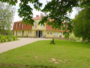 una casa con un césped verde delante de ella en Landhotel Am Peetscher See, en Mirow