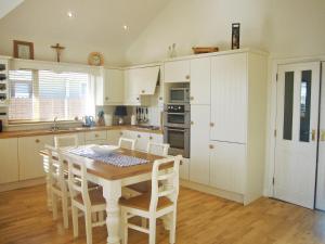a kitchen with a wooden table and white cabinets at Dacha Holiday Home by Trident Holiday Homes in Ardmore