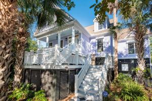 a house with a white deck and palm trees at 114 W Huron - Sand Castle - Saltwater Pool - Heated upon request in Folly Beach