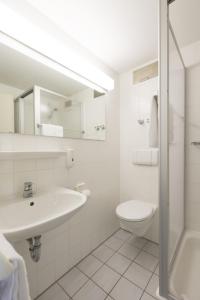 a white bathroom with a sink and a toilet at Sportpark Hotel Isernhagen in Isernhagen