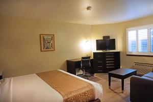 a hotel room with a bed and a desk with a television at Travelodge by Wyndham Concord in Concord
