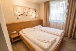 sypialnia z łóżkiem z białą pościelą i oknem w obiekcie Max Residence Zell am See - Steinbock Lodges w mieście Zell am See