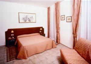 1 dormitorio con 1 cama y 1 silla en Hotel San Pietro, en Asís