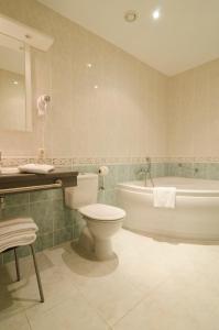 ein Badezimmer mit einem WC, einer Badewanne und einem Waschbecken in der Unterkunft Hotel Prins Boudewijn in Knokke-Heist