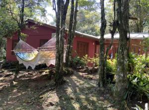 a red house with a hammock in the woods at Refúgio da natureza in São Francisco de Paula