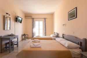 a room with three beds and a desk and a television at Vanas Apartments in Spetses