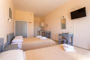 a room with three beds and a tv on the wall at Vanas Apartments in Spetses