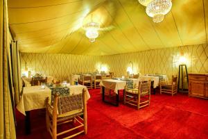 una tenda con sala da pranzo con tavoli e sedie. di Madu Luxury Desert Camp a Merzouga