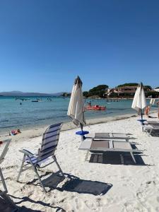 a group of chairs and umbrellas on a beach at Terza Spiaggia & La Filasca - Apartments in Golfo Aranci