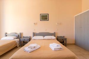 two beds in a room with towels on them at Vanas Apartments in Spetses