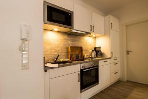 eine Küche mit weißen Schränken und einer Mikrowelle in der Unterkunft Frau Clara Haus - Ecke 2 in Eckernförde