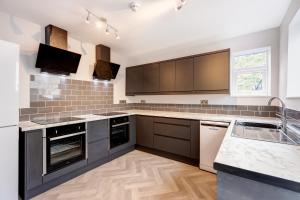 a kitchen with a stove top oven, microwave, sink and dishwasher at Bondgate Hotel East Midlands Airport in Castle Donington