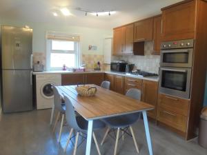 Il comprend une cuisine avec une table et des chaises en bois. dans l'établissement 11B Beachside, à Eastbourne