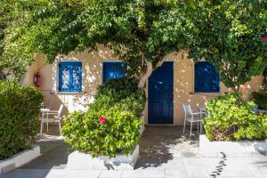 a building with blue doors and chairs and trees at Vanas Apartments in Spetses