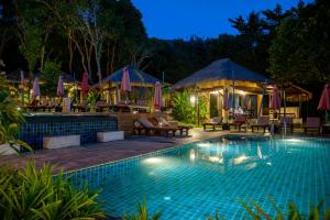 ein Pool mit Stühlen und Sonnenschirmen in der Nacht in der Unterkunft LaLaanta Hideaway Resort in Ko Lanta + 37 Fotos