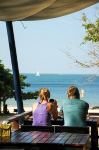 Ein Mann und eine Frau sitzen auf einer Bank und sehen auf den Ozean. in der Unterkunft LaLaanta Hideaway Resort in Ko Lanta