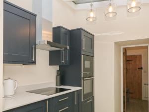 a kitchen with black cabinets and white counter tops at 3 Old Hall Cottages in Bakewell
