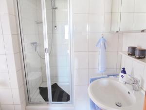 ein weißes Bad mit einer Dusche und einem Waschbecken in der Unterkunft Haus Scheel in Burg auf Fehmarn