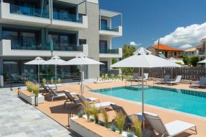a swimming pool with chairs and umbrellas next to a building at KN Ionian Suites in Nikiana