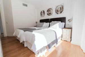 a white bedroom with a large bed and a wooden floor at Polo Apartments 8B in Marbella