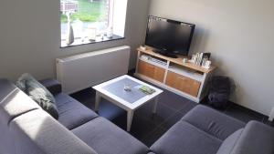 a living room with a couch and a tv at vakantiewoning onZENhof in Heuvelland