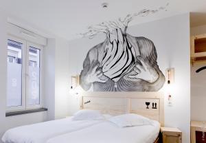 um quarto com uma cama com um quadro na parede em Hôtel Graffalgar em Estrasburgo